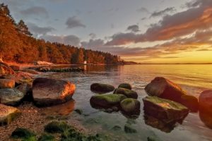 aurinko laskee meren rannalla