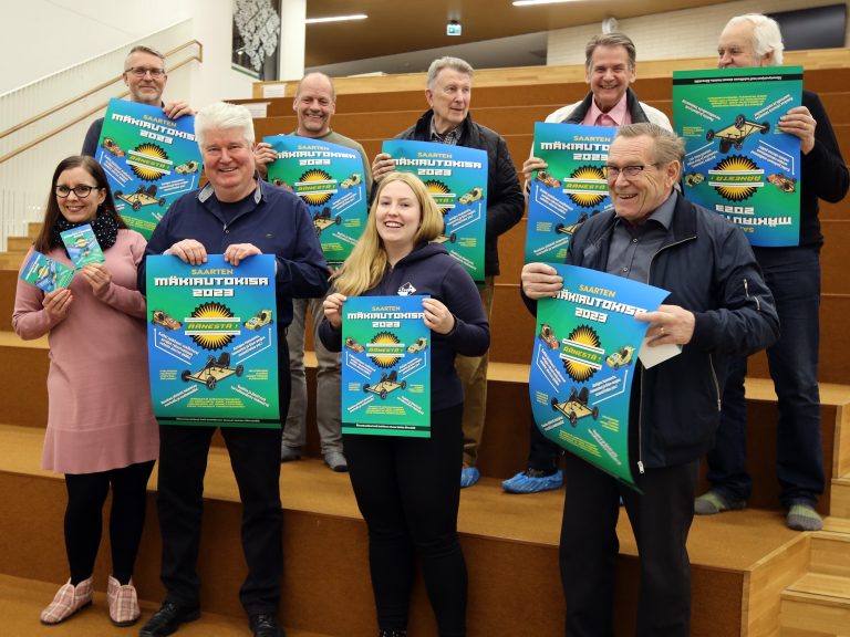 kouluvaarit ja muut osallistujat esittelevät mäkiautokisan julistetta