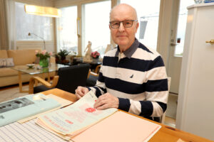 mies istuu pöydän takana, pöydällä on papereita