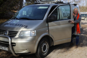 nainen seisoo pakettiauton vierellä ja on nousemassa autoon