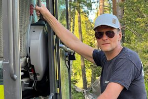 lippalakkipäinen mies katsoo aurinkolasien takaa kameraan.